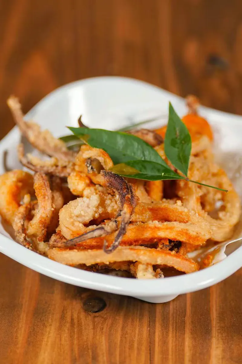Golden crispy salt and pepper fried squid rings on lined white plate at One More Bite Dumpling, a Chinese Restaurant in Yucaipa
